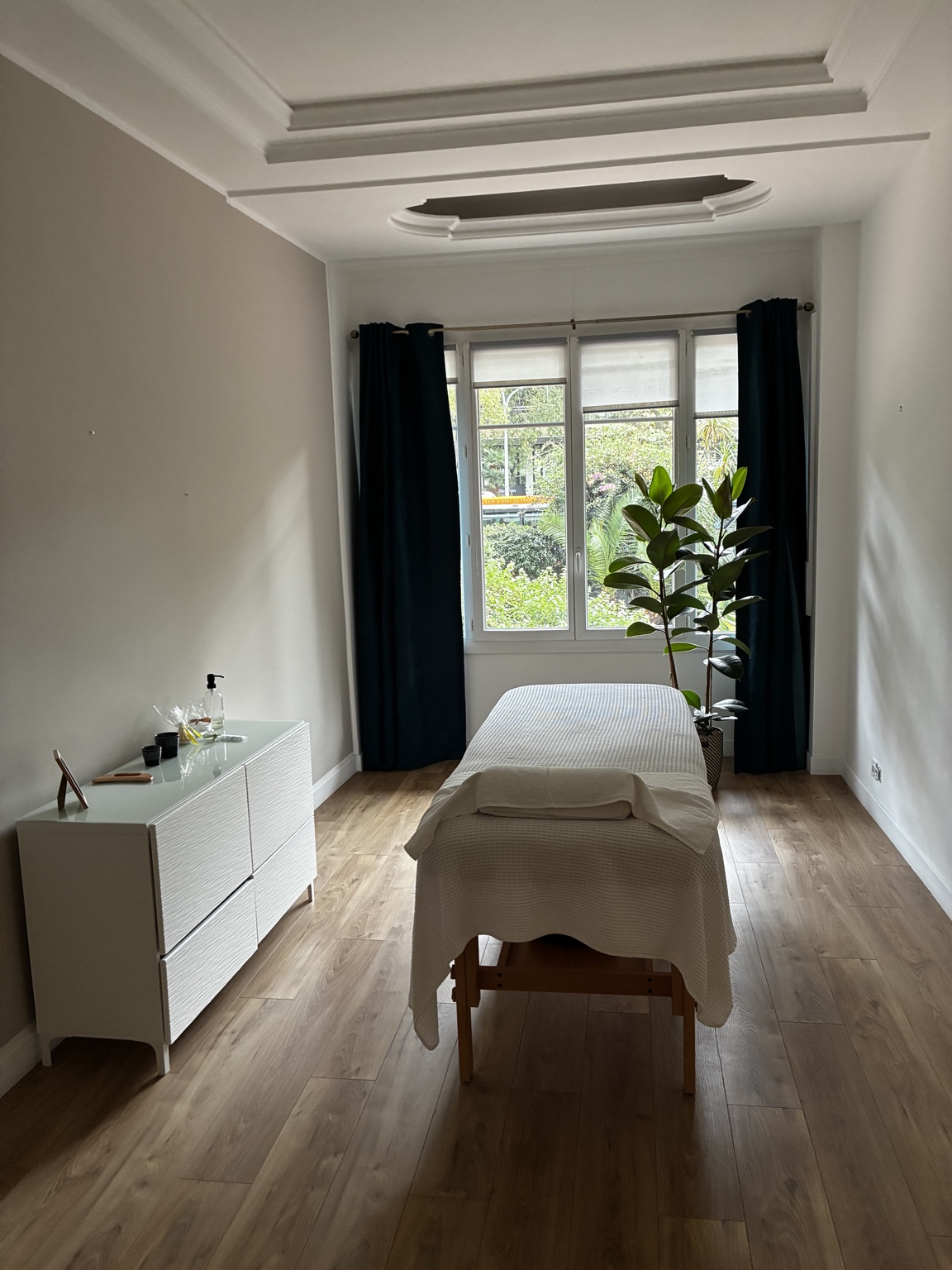 Salle de soins avec table de soin et fenêtre donnant sur la végétation